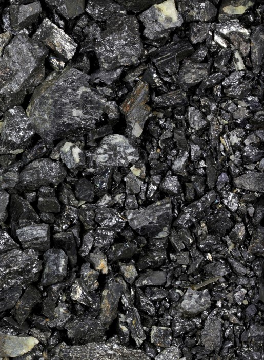 Mined coltan covers the ground, its graphite gray color making it look like charcoal.